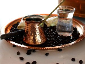 Турка, кофейные зерна и стакан воды